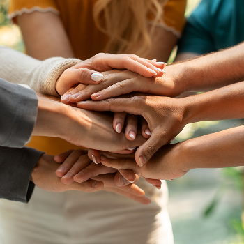Mãos de diversas pessoas unidas, representando o compromisso da Orit com as pessoas e o trabalho coletivo sustentável